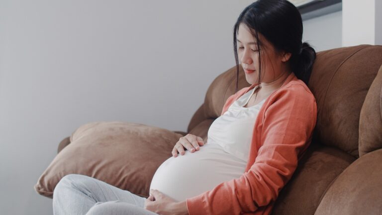 Young Asian Pregnant woman holding her belly talking with her ch - Serenity Clinic - Serenity Clinic